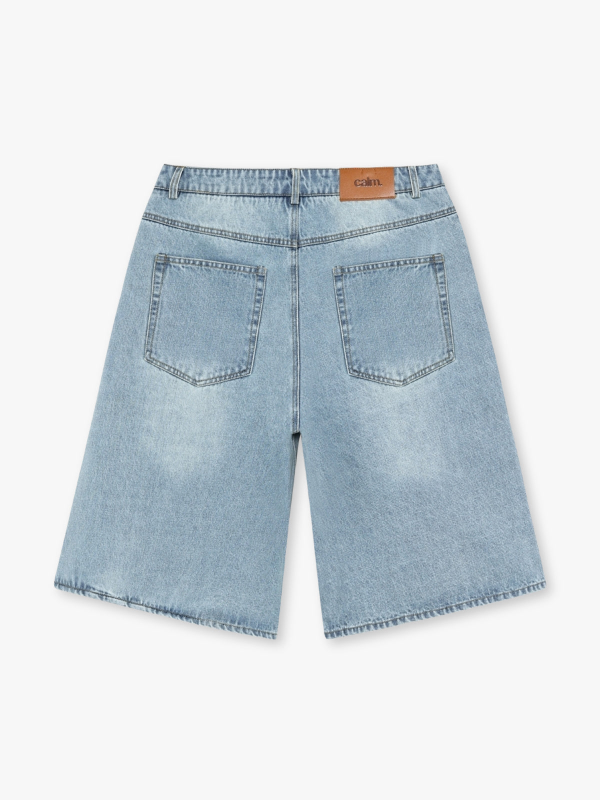 Baggy jorts in light wash denim with Calm logo leather patch seen from the back